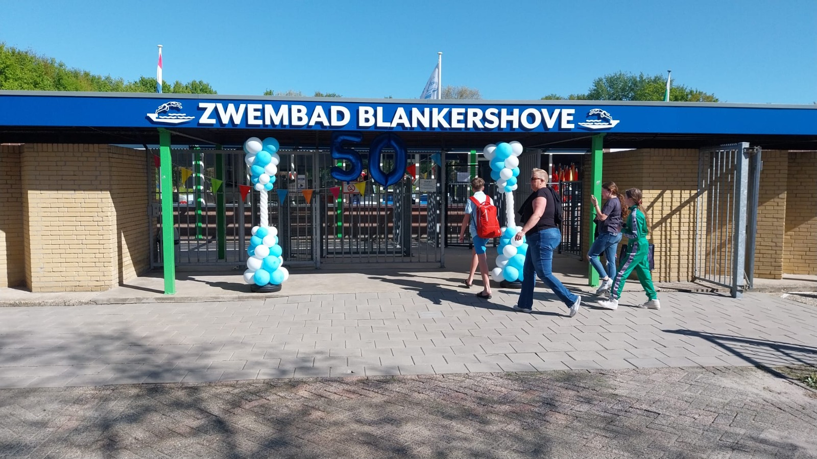 Bezoekers gaan via de versierde entree van Blankershove het Gastelse zwembad binnen. Ondanks het vroege uur is het binnen al aardig gevuld.