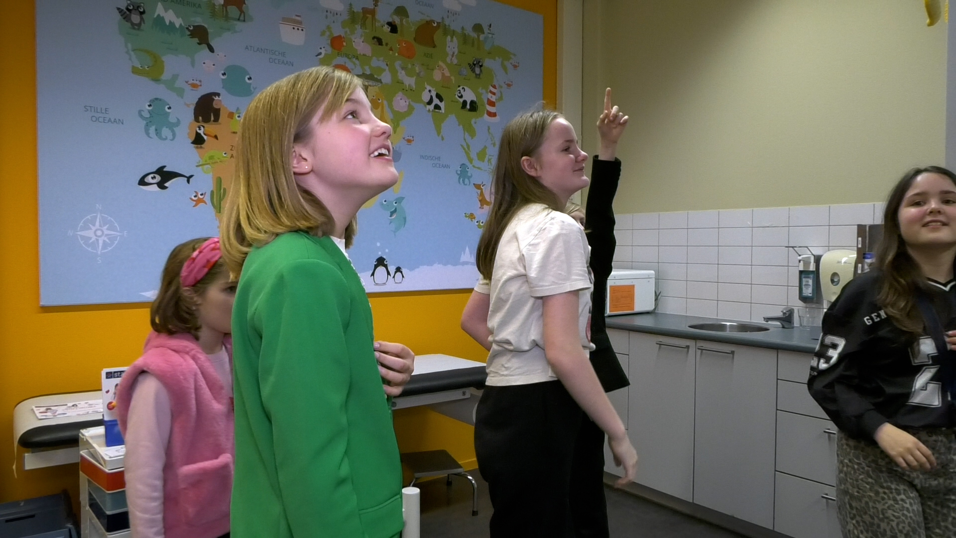 In de kamer hangt een grote wereldkaart met dieren erop.