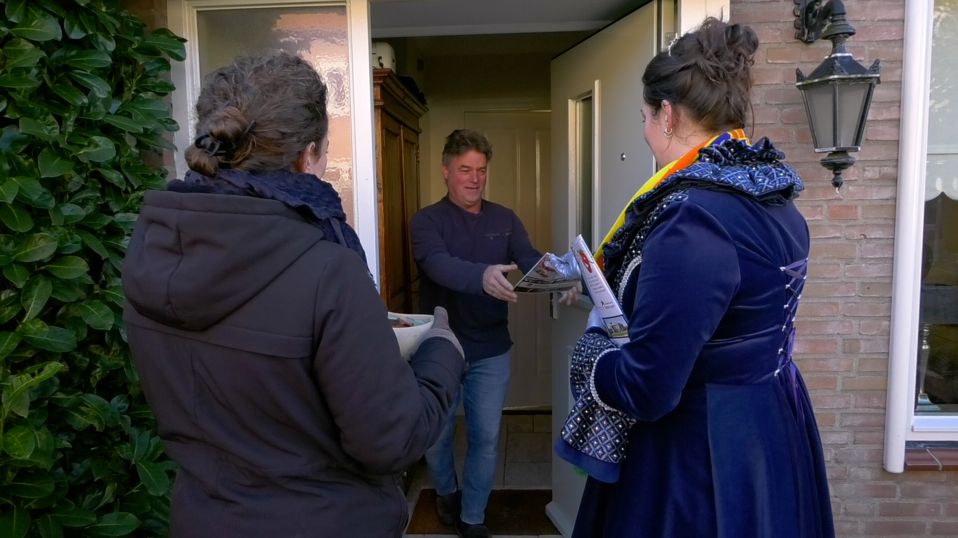 Prinses Danique rijkt de carnavalskrant uit aan een inwoner.