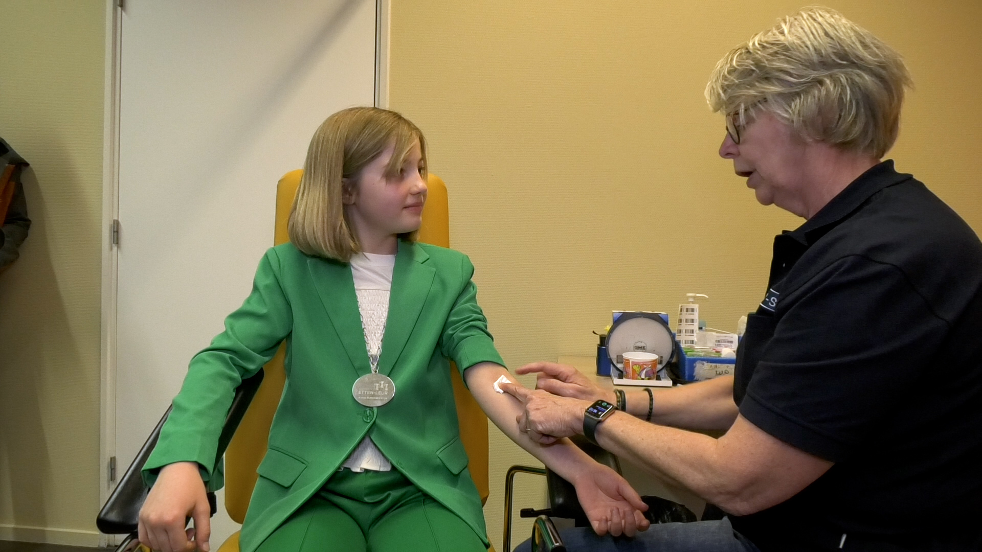 Tijdens de opening krijgt jeugdburgemeester Eline uitleg hoe het prikken in zijn werk gaat