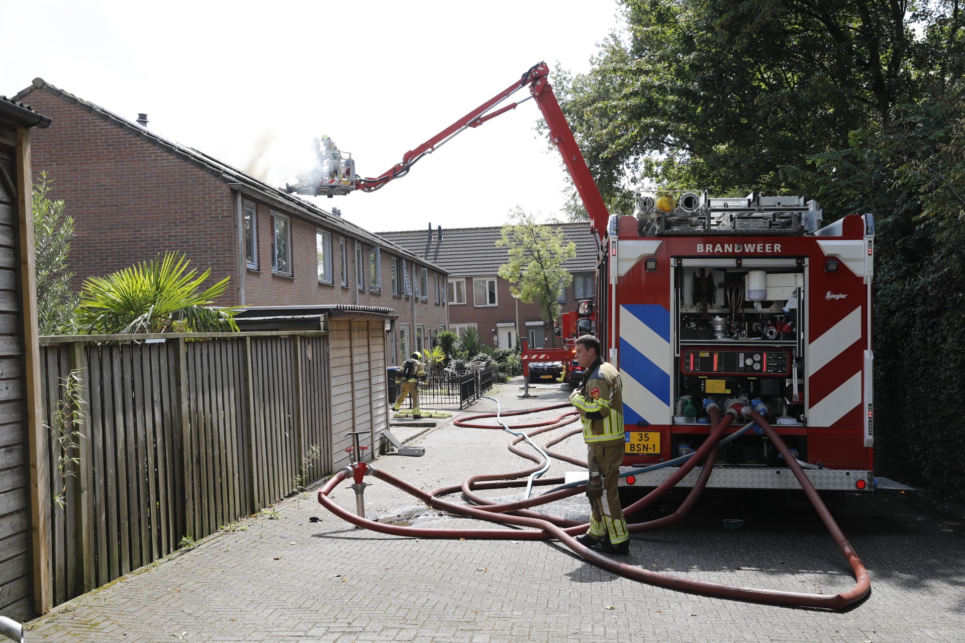 Een hoogwerker is de nok van het dak nog aan het controleren.